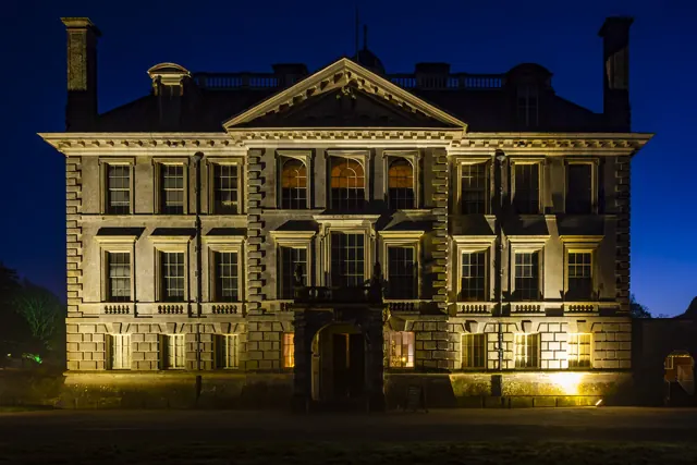 Stone estate facade washed with warm architectural lighting at night