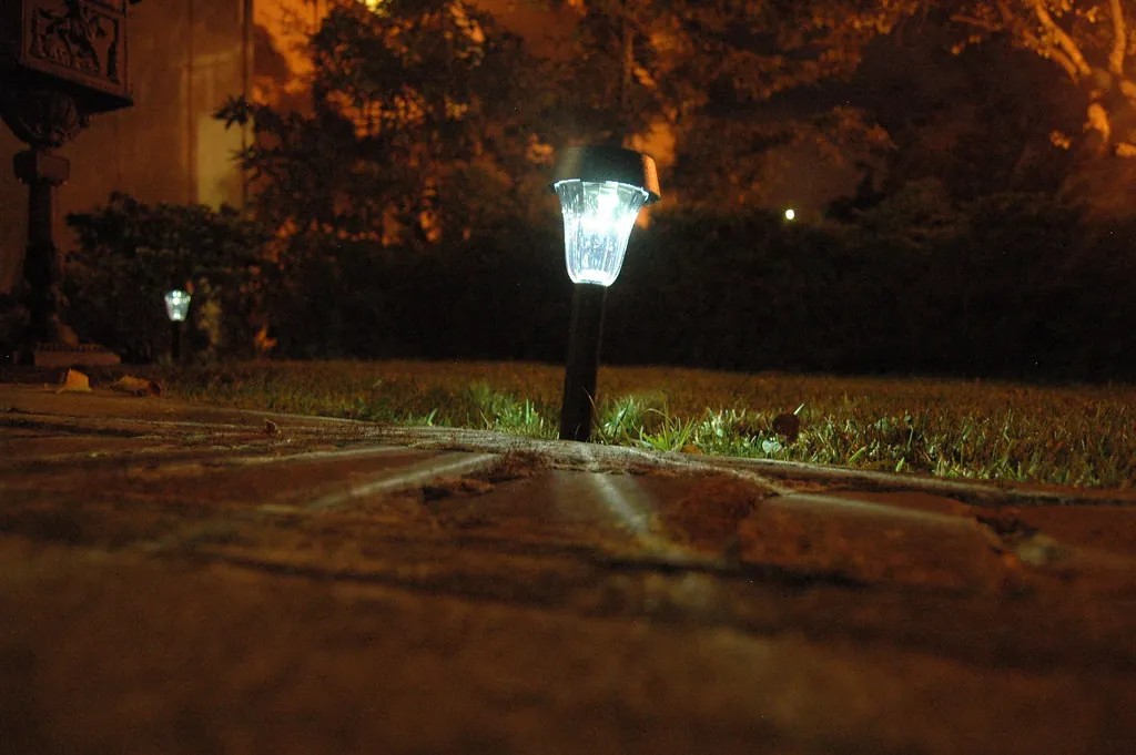 Close-up of a path light glowing on a lawn at night