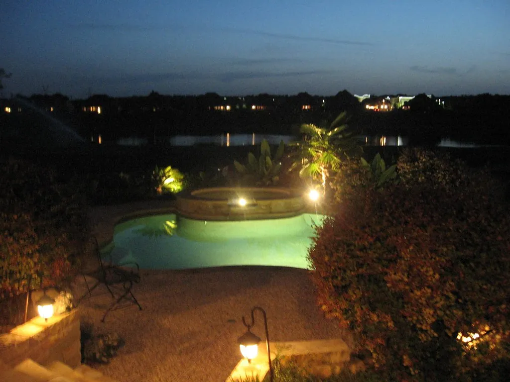 Pool and garden with path lights seen from above at dusk