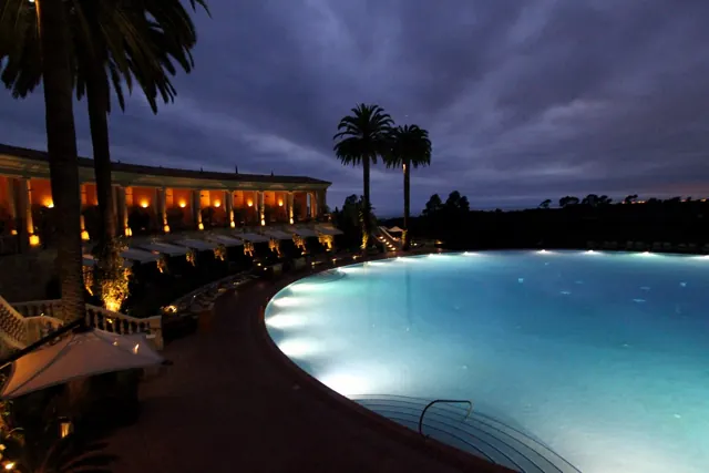 Lit resort pool and palms at night